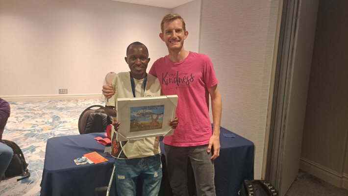 A photo of me and Muhue with the DjangoCon Africa art that was used to boost donations to Black Python Devs.