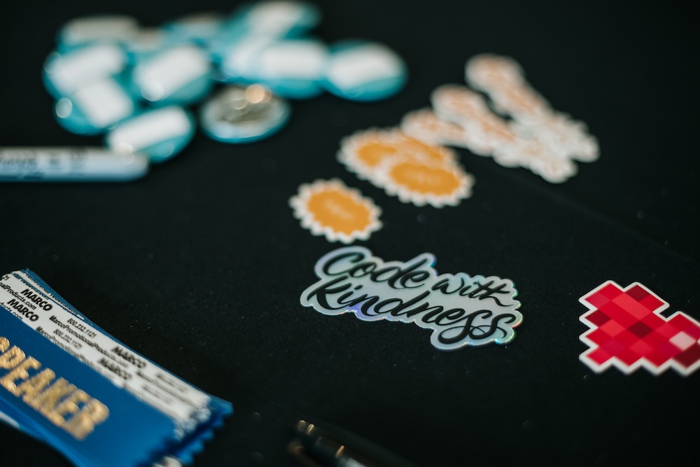The DjangoCon US 2022 stickers, the main one reading, Code with Kindness. <br />Credit: <a href="https://bartpawlik.format.com/">Bartek Pawlik</a>
